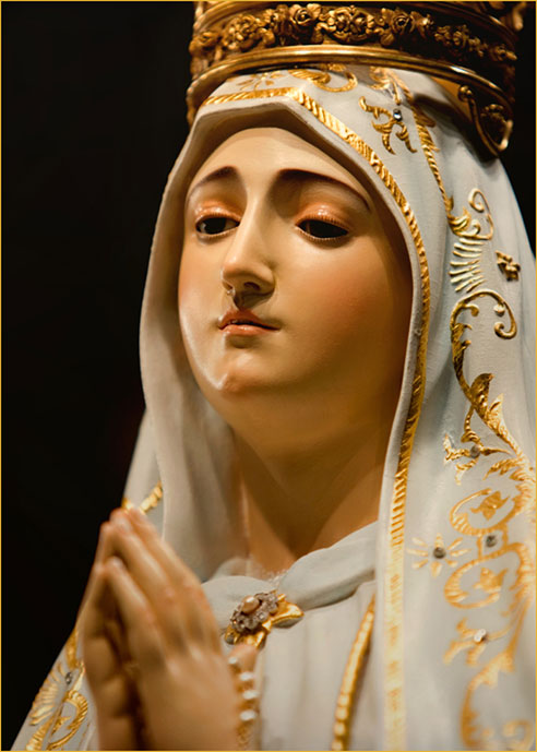 A statue of Our Lady of Fatima, Queen of Peace, hands joined in prayer